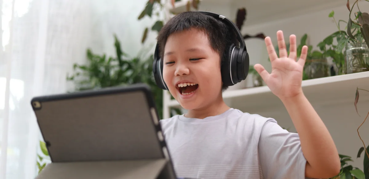 Elementary Student waiving at his online class at home